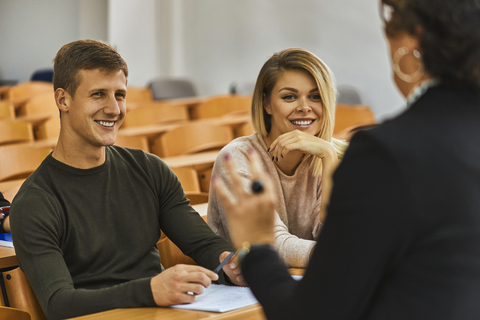 Lächelnde Studenten und Dozenten im Hörsaal einer Universität, lizenzfreies Stockfoto