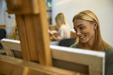 Lächelnde Schülerin malt auf der Staffelei im Kunstunterricht - ZEDF01008