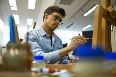 Student painting on easel in art class - ZEDF01010