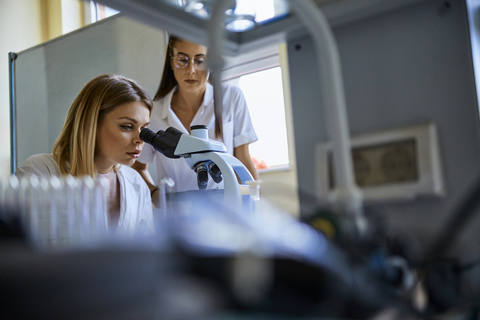 Zwei junge Frauen mit Mikroskop im Labor, lizenzfreies Stockfoto
