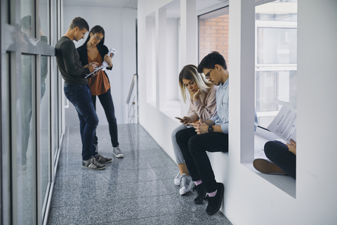 Group of students in hallway with documents and cell phones stock photo