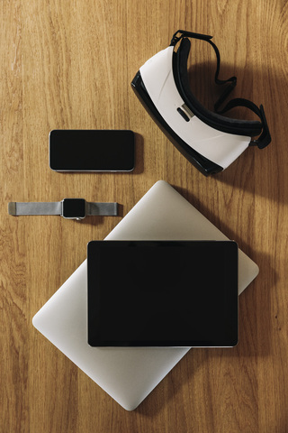 Smartphone, Smartwatch, Tablet, Laptop und Virtual-Reality-Brille auf Holztischplatte, lizenzfreies Stockfoto
