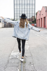 Back view of fashionable young woman wearing hat balancing on rail - GIOF03525