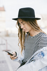 Portrait of fashionable young woman wearing hat using smartphone - GIOF03531