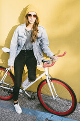 Portrait of fashionable young woman with bicycle - GIOF03545