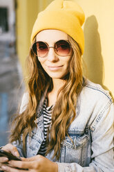 Portrait of fashionable young woman wearing yellow cap and sunglasses - GIOF03547