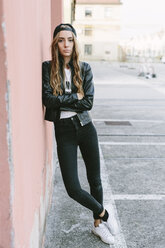 Fashionable young woman wearing baseball cap leaning against wall - GIOF03551