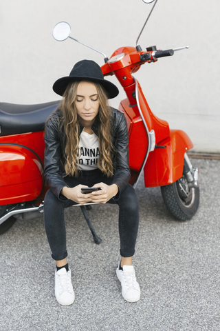 Modische junge Frau mit rotem Motorroller und Mobiltelefon, lizenzfreies Stockfoto