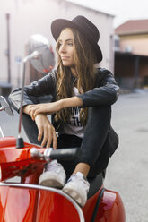 Portrait of fashionable young woman sitting on red motor scooter - GIOF03561