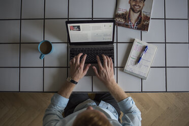 Freelance businessman working on his laptop at home, top view - MOMF00302