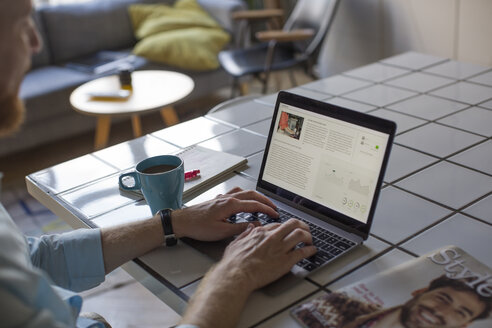 Freelance businessman working on his laptop at home, partial view - MOMF00310