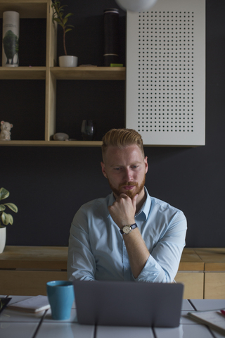 Pensive freelance businessman working on his laptop at home stock photo