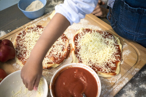 Mädchen in der Küche, das lernt, wie man Pizza backt und Käse streut - MOEF00302