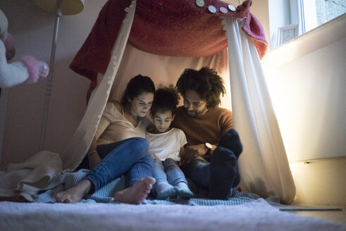 Parents sitting in children's room with daughter, looking at digital tablet - MOEF00309