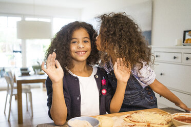 Little girl kissing sister in kitchen, baking pizza - MOEF00315