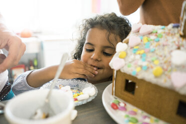 Kleines Mädchen nascht Süßigkeiten für ein Weihnachtslebkuchenhaus - MOEF00329