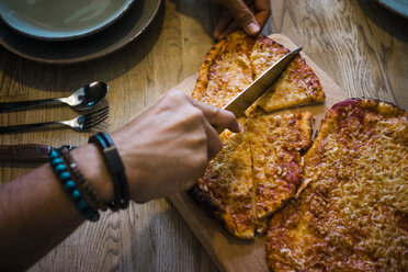 Hand cutting crispy homemade pizza with a knife - MOEF00331