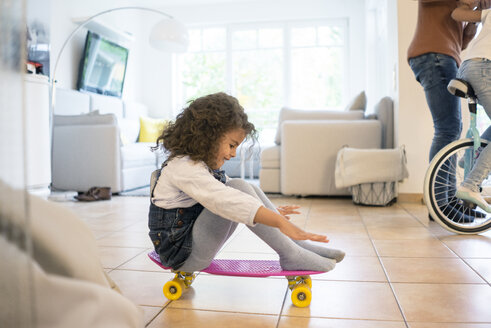 Kleines Mädchen sitzt auf einem Skateboard und hat Spaß - MOEF00333