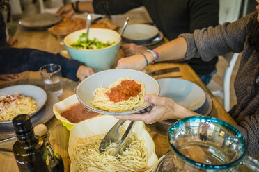 Family sitting at table with spaghetti and tomato sauce - MOEF00334