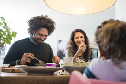 Glückliche Familie beim gemeinsamen Essen von Pizza und Pasta, lizenzfreies Stockfoto