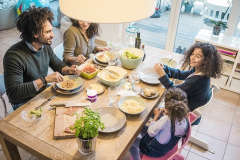Glückliche Familie beim gemeinsamen Essen von Pizza und Pasta, lizenzfreies Stockfoto