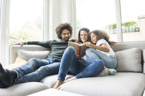 Glückliche Familie sitzt auf der Couch und liest ein Buch - MOEF00348