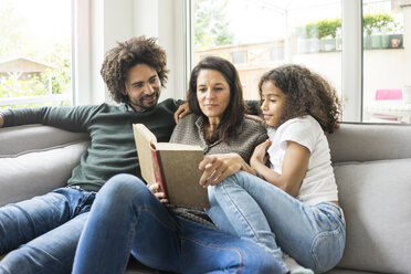 Glückliche Familie sitzt auf der Couch und liest ein Buch - MOEF00349