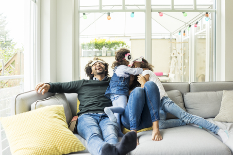 Happy family sitting on couch, wearing animal masks stock photo