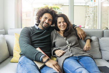 Couple sitting on couch reading book - MOEF00360