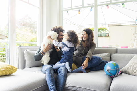 Glückliche Familie mit Hund sitzt zusammen im gemütlichen Wohnzimmer, lizenzfreies Stockfoto