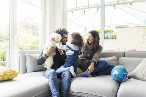 Happy family with dog sitting together in cozy living room - MOEF00366