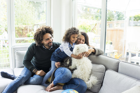 Happy family with dog sitting together in cozy living room - MOEF00367