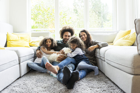 Happy family with dog sitting together in cozy living room - MOEF00370