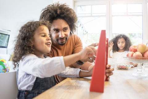 Vater sitzt mit seiner Tochter am Tisch und lernt, mit einem Rechenschieber zu rechnen, lizenzfreies Stockfoto