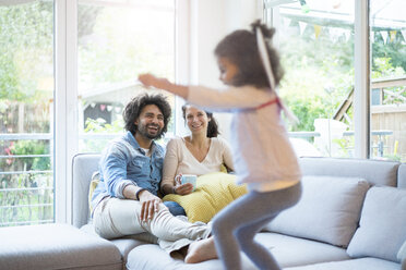 Die Eltern sitzen auf der Couch, während die Tochter springt und Spaß hat - MOEF00421