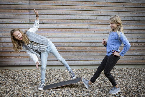 Two girls with skateboard in front of a wooden facade - OJF00214