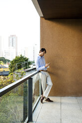 Geschäftsmann steht auf einem Balkon und benutzt ein Smartphone - VABF01362