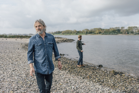 Father and son spending time together, son skipping pebbles stock photo