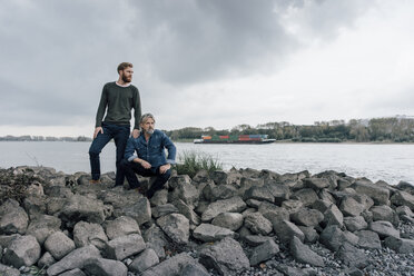 Father and son spending time together outdoors, taking a break, sitting on stones - KNSF02897