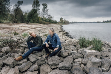 Father and son spending time together outdoors, taking a break, sitting on stones - KNSF02904