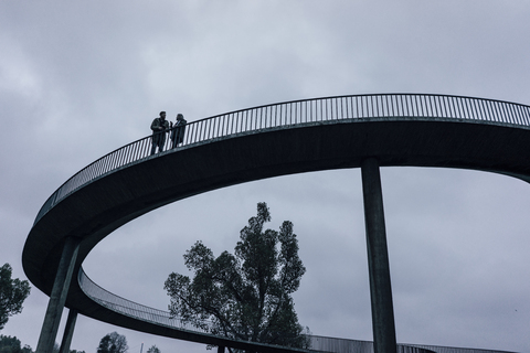 Zwei Geschäftsleute stehen auf einer dunklen Brücke und haben eine Besprechung, lizenzfreies Stockfoto