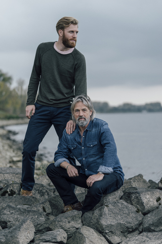 Vater und Sohn verbringen Zeit miteinander im Freien, machen eine Pause, sitzen auf Steinen, lizenzfreies Stockfoto