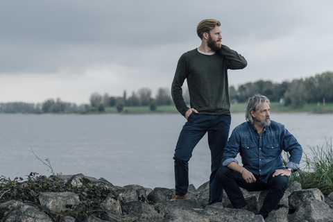 Vater und Sohn verbringen Zeit miteinander im Freien, machen eine Pause, sitzen auf Steinen, lizenzfreies Stockfoto