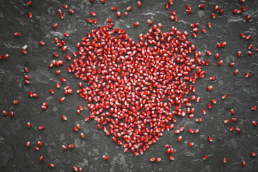 Heart shaped of pomegranate seeds on slate - ASF06124