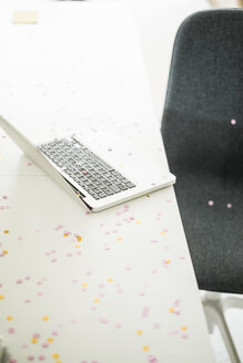 Confetti on desk with laptop in office - JOSF01954