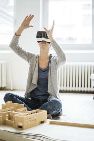 Frau im Büro mit Architekturmodell und VR-Brille, lizenzfreies Stockfoto