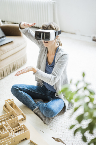 Woman in office with architectural model wearing VR glasses stock photo