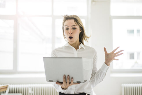 Amazed woman holding laptop - JOSF01992