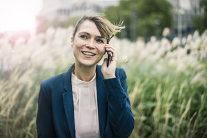 Lächelnde Geschäftsfrau am Mobiltelefon im Freien - JOSF02006