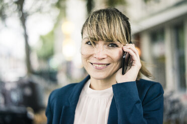 Portrait of smiling businesswoman on cell phone outdoors - JOSF02011